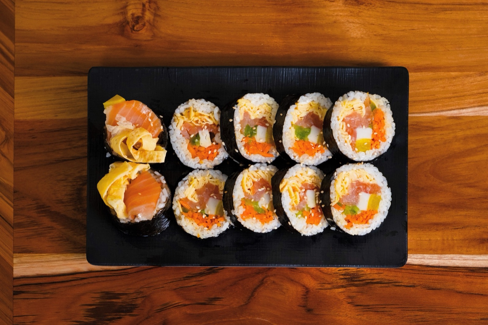 Lachs-Kimbap auf schwarzer Platte
